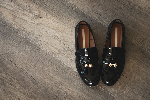 Black female moccasins shoes over wooden background, top view. Concept of fashion, style, walking barefoot- Copy space