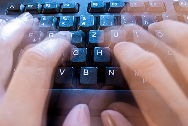 Time lapse of fingers typing on modern black keyboard stock photo
