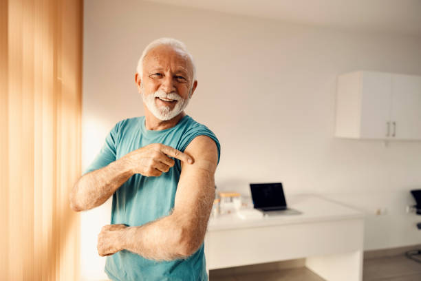 istock A happy senior man in doctor's office pointing at his vaccinated shoulder. Immunization and vaccination. 1362337149
