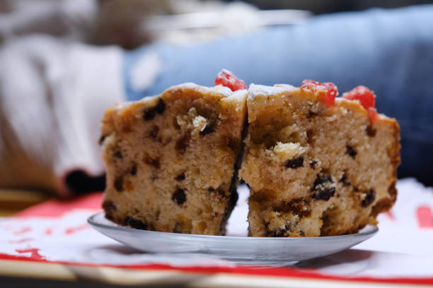 Woman is sitting on the sofa with a cup of tea, a slice of homemade cake and knitting