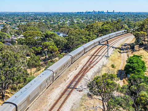 Aerial view luxury Overland Passenger Train departing for Melbourne, Sydney & Brisbane. City CBD in distant background. ID & logos edited