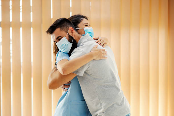 Happy man hugging his female doctor at hospital. Medical attention, medical service and health care. stock photo