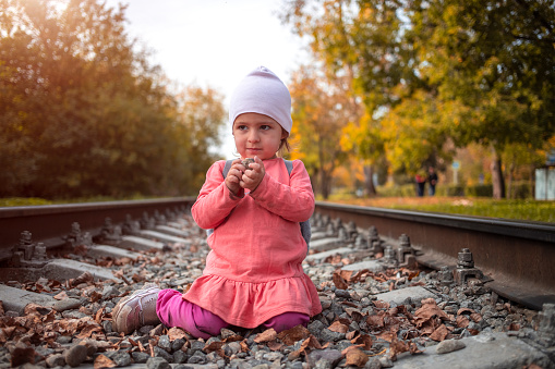 toddler girl plays on railroad alone autumn day