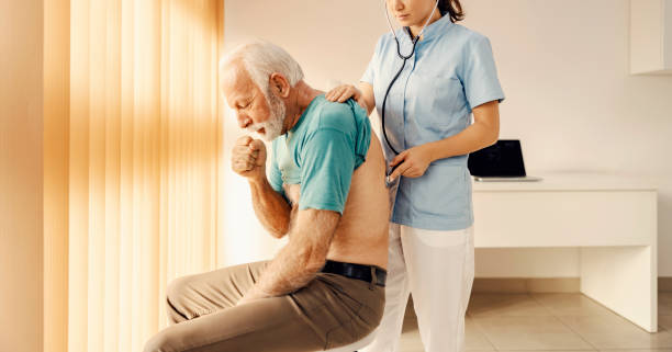 a sick old man coughing and getting medical attention by a female doctor in doctor's office. heath care, medical support and medical service. - clinic men healthcare and medicine doctor imagens e fotografias de stock