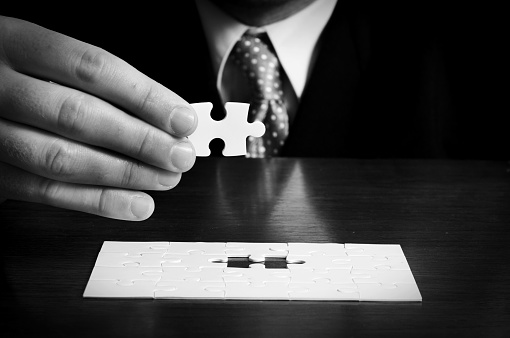 a businessman holding the last piece of a jigsaw puzzle.
