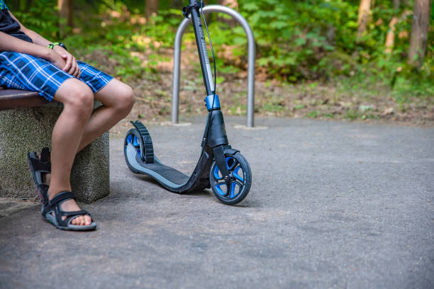 istock Walk in the park on a scooter. A young guy sits on a bench and rests while walking on a smokat. Ecology and ecological transport concept 1362340597