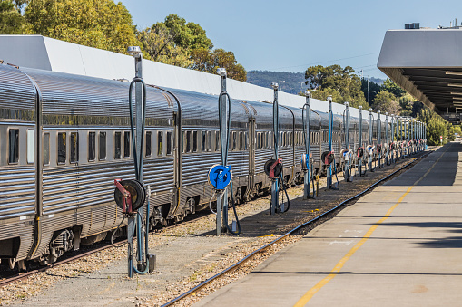 Luxury Overland Passenger Train being prepared in station platform for departure to Melbourne, Sydney & Brisbane. Alongside the train are a series of poles with water hoses to service each carriage on the train.  ID & logos edited