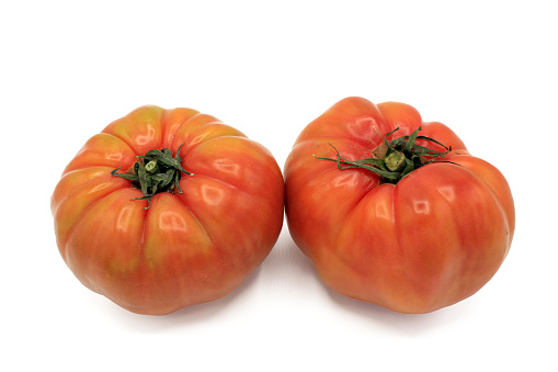 Two whole pink tomatoes isolated on white background