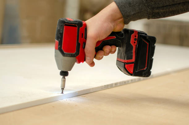 istock A man with a cordless screwdriver. Screws a self-tapping screw into a tree 1362344438