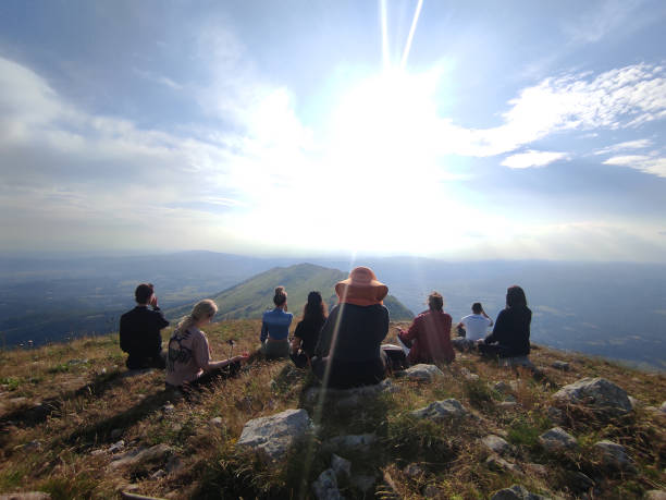 Group of friends taking a yoga class on top of a mountain peak, during a sunny day. Yoga - concept. Phone photography themes.
