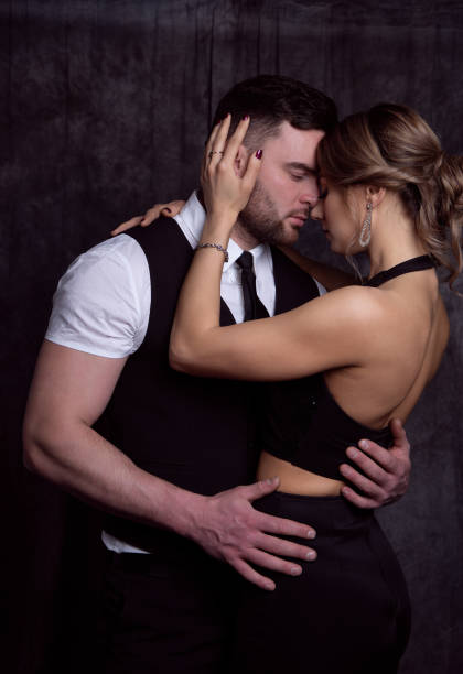 элегантные мужчина и женщина, закрывая глаза от удовольствия, нежно обнимают друг друга перед поцелуем - couple sensuality embracing heterosexual couple стоковые фото и изображения