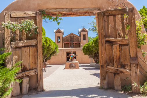 Old adobe church (El Santuario de Chimayo) with gate located in Chimayo, New Mexico where there is always a pilgrimage for Easter. Church is known to have a hole in the floor with dirt in it.  The dirt is supposed to have healing properties in which people's health issues are cured. Church is known for multiple pilgrimages a year.