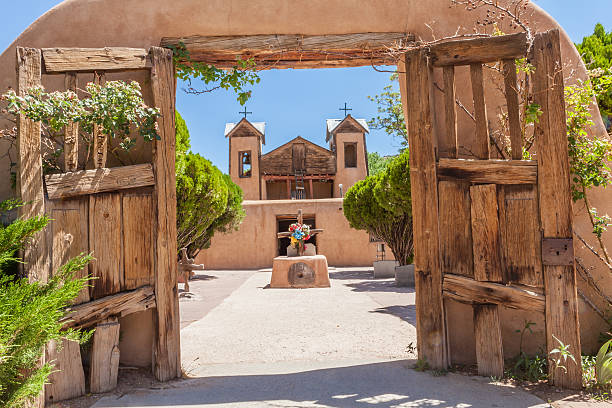 El Santuario do Chimayo church in New Mexico Old adobe church (El Santuario de Chimayo) with gate located in Chimayo, New Mexico where there is always a pilgrimage for Easter. Church is known to have a hole in the floor with dirt in it.  The dirt is supposed to have healing properties in which people's health issues are cured. Church is known for multiple pilgrimages a year. santa fe new mexico stock pictures, royalty-free photos & images