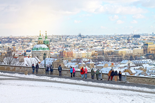View of winters snowy Prague City, Czech Republic. Christmas time in Prague. Walking tourists see from Hradcany on old part of Prague - Mala Strana.