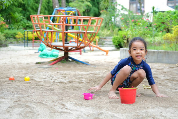 Asian kid showing happy expression while playing beach sand in the outdoor playground Asian kid showing happy expression while playing beach sand in the outdoor playground keluarga stock pictures, royalty-free photos & images