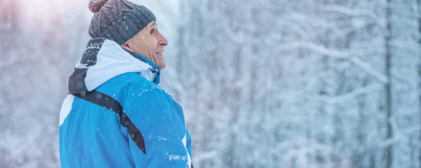 istock Side view of old hiker standing in winter forest and looking aside. 1362359257
