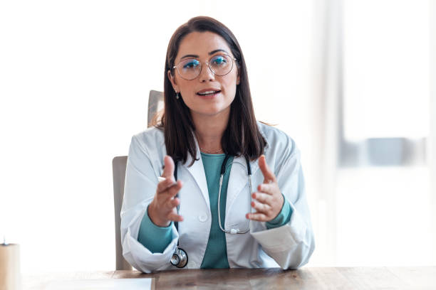 istock Attractive female doctor smiling looking at camera while working with laptop in the consultation. 1362359915