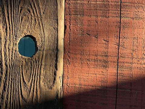 Background texture of old wooden fence with a hole. Photo with soft sunlight and copy space. Selective focus.