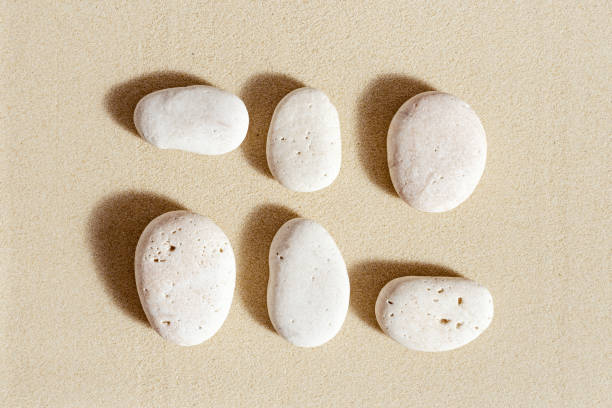 istock Sea stones neutral beige color on natural fine sand background. Square composition from natural white pebbles, monochrome tones 1362364366