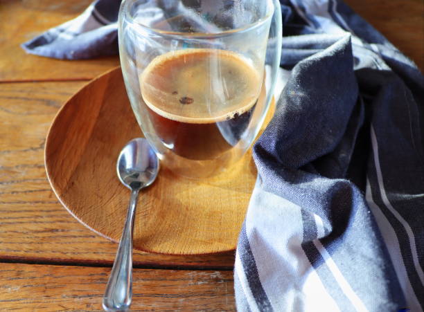 Transparent double wall glass mug with espresso coffee on rustic wooden background