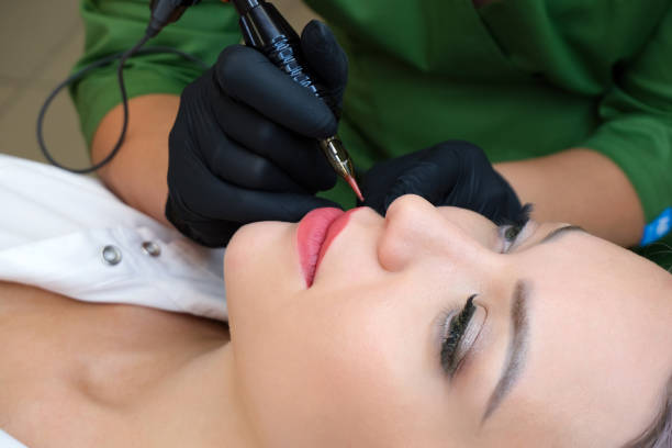 istock Young woman having permanent makeup on her lips at the beauticians salon. 1362365385