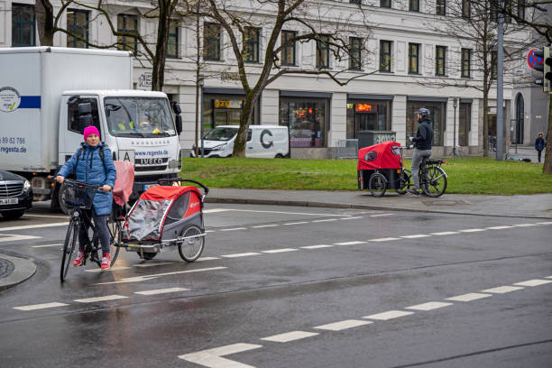 A man and a woman on two different kind of bikes used to transport children on a cold winter day in the center of the German city Munich