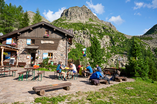 Palù del Fersina, Italy - August 08, 2021: hikers get some rest outside the Sette Selle Mountain Hut. The mountain hut is popular stop among the Translagorai hikers.