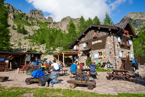 Palù del Fersina, Italy - August 08, 2021: hikers get some rest outside the Sette Selle Mountain Hut. The mountain hut is popular milestone among the Translagorai hikers.