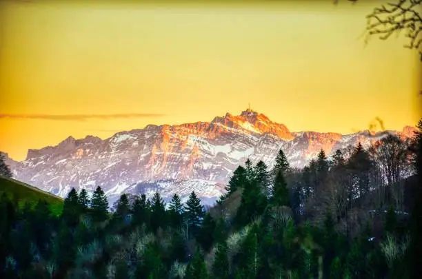 sunset in the mountains. The Santis mountain in the Appenzell Alps lights up in the last light. snow on the peak.