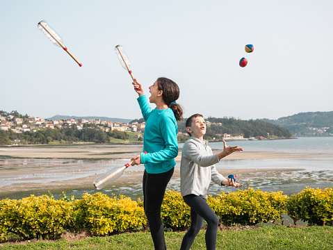 young boy and girl playing in the garden, juggling with balls and home made juggling clubs, sports and active lifestyle concept