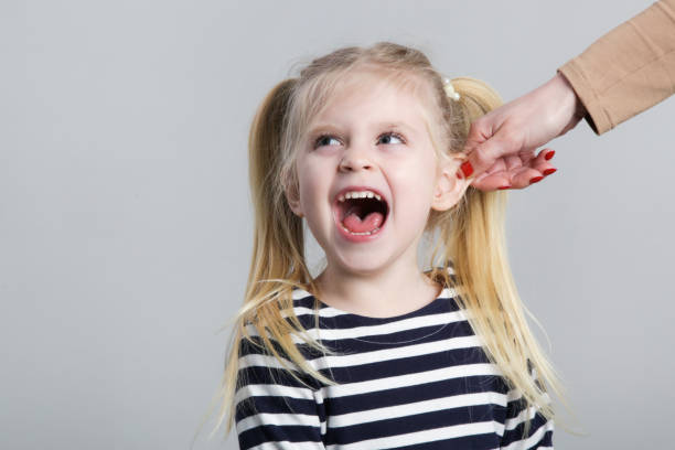 istock Disobedient little girl being punished by ear pulling, studio shot 1362379628