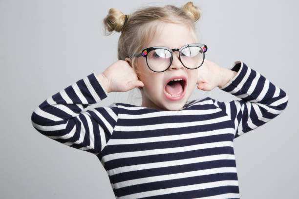 istock Cute little nerd child covering ears with hands and screaming, studio shot. 1362381880