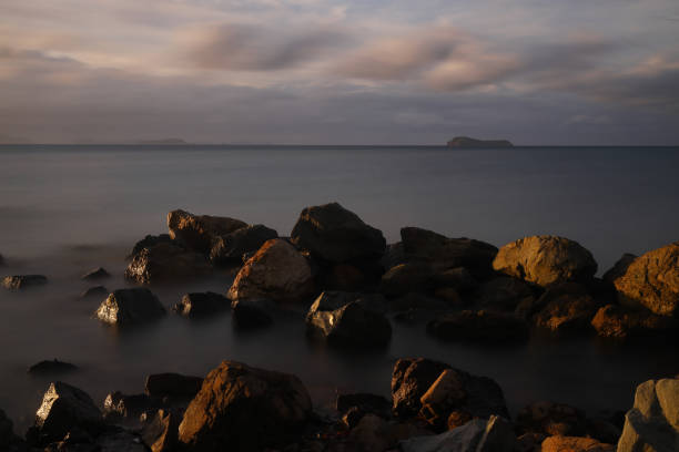 image à longue exposition du paysage marin spectaculaire avec de la roche en arrière-plan du coucher du soleil. magnifique paysage marin de lever ou de coucher de soleil sur la mer paysage marin épique de l’aube avec des rochers au premier plan. - long exposure rock cloud sky photos et images de collection