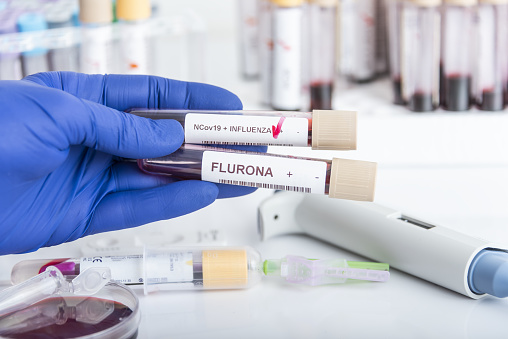 Doctor's hands hold blood samples of the new variant omicron plus flu FLURONA, covid19, coronavirus. Selective approach to the sample tube