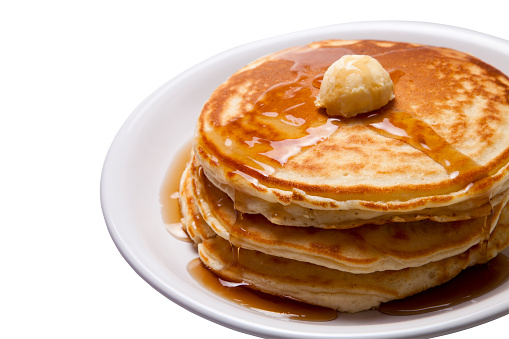 Stack of three pancakes with syrup and dollop of butter, on a plate, isolated on white