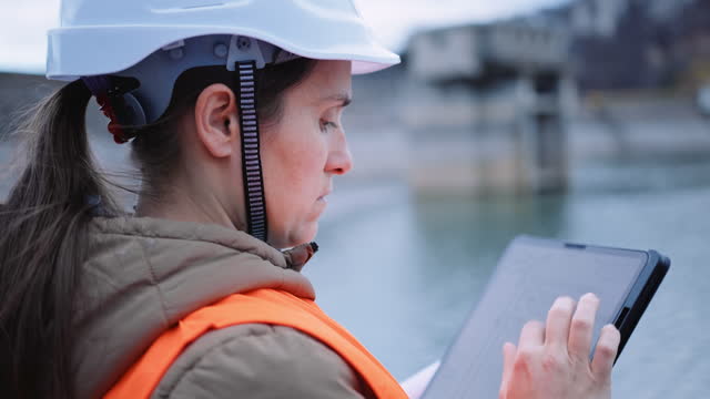 Female engineer working in hydroelectric dam. Ecology orientated. Renewable energy systems.