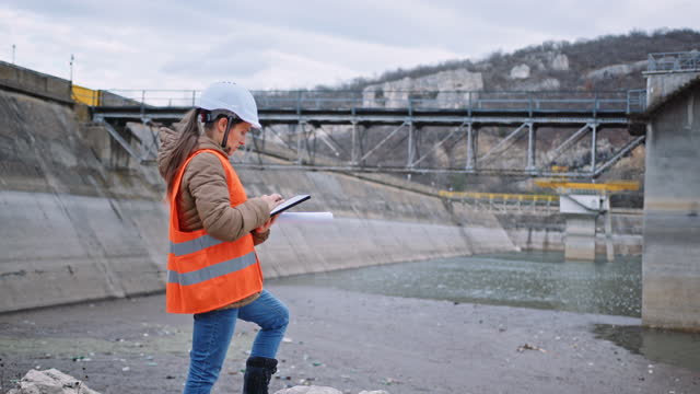 Female engineer working in hydroelectric dam. Ecology orientated. Renewable energy systems.