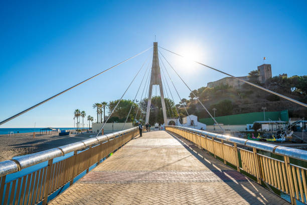 Fuengirola cable Armada bridge over Fuengirola river  in Costa del Sol of Malaga in Spain. The cable bridge was build in 2006 to allow pedestrians to keep the foodpath promenade along the Fuengirola beach shore. The bridge shound not disturb the natural river flood with 90 meters wide. Today is an iconic landmark in Fuengirola