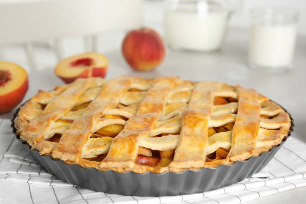 Delicious fresh peach pie on light kitchen table, closeup Delicious fresh peach pie on light kitchen table, closeup crostata stock pictures, royalty-free photos & images