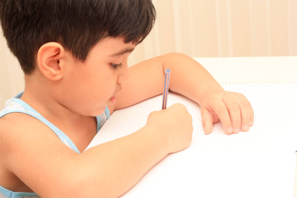 Little boy sitting and drawing with color crayons