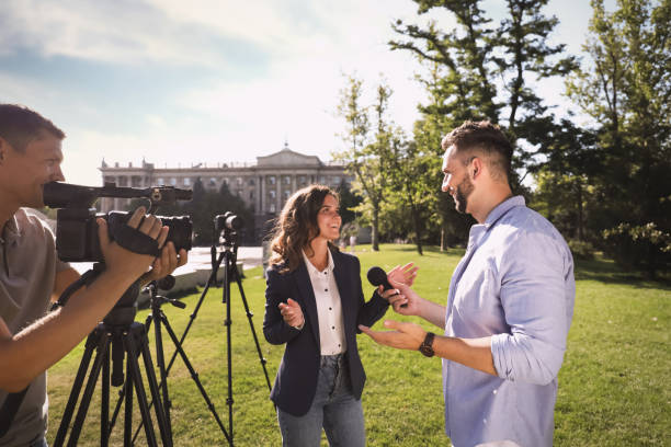 istock Professional journalist and operator with video camera taking interview outdoors 1362400541