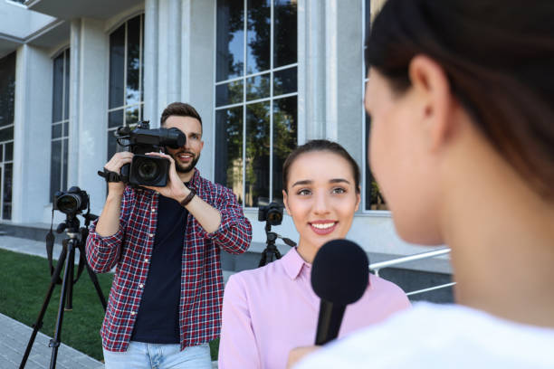 istock Professional journalist and operator with video camera taking interview outdoors 1362401695
