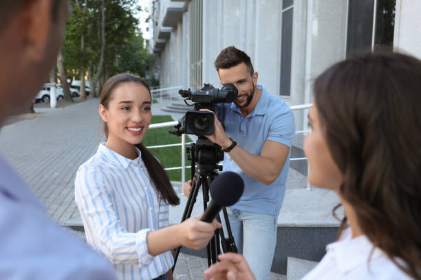 istock Professional journalist and operator with video camera taking interview outdoors 1362401844