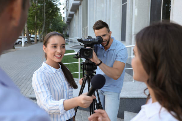 Professional journalist and operator with video camera taking interview outdoors Professional journalist and operator with video camera taking interview outdoors journalist stock pictures, royalty-free photos & images
