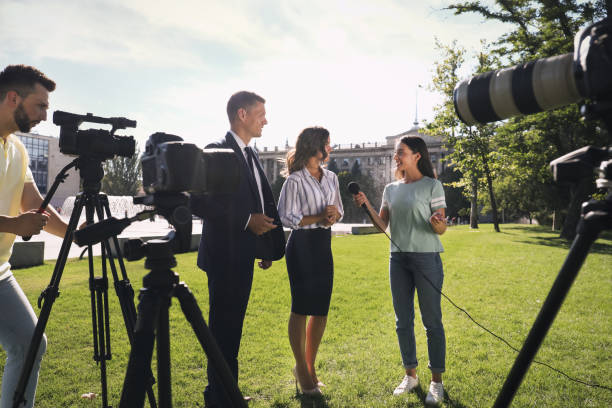istock Professional journalist and operator with video camera taking interview outdoors 1362401922