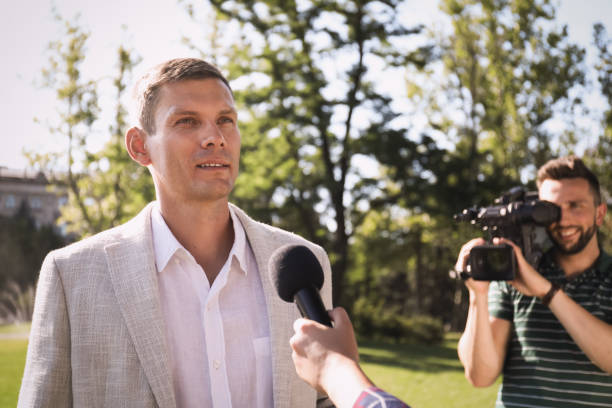 istock Professional journalist and operator with video camera taking interview outdoors 1362404595