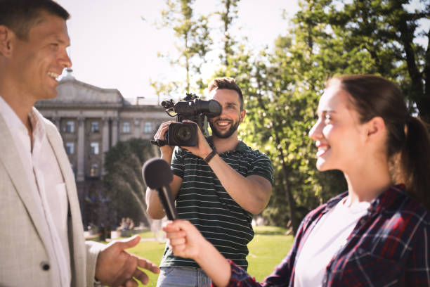 istock Professional journalist and operator with video camera taking interview outdoors 1362404626