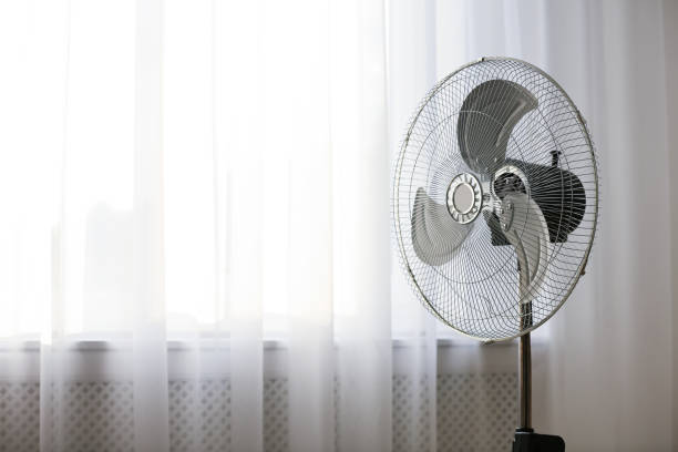 istock Modern electric fan near window indoors. Space for text 1362404708