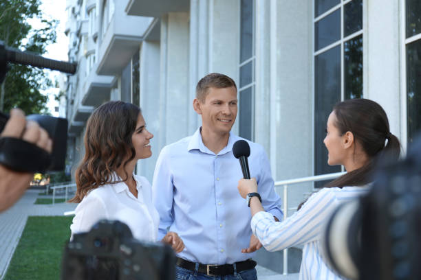 istock Professional journalist and operator with video camera taking interview outdoors 1362404796