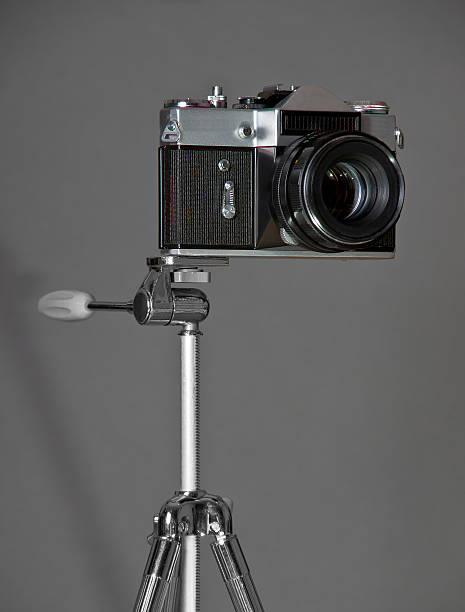 istock Old film camera and retro steel tripod on grey background 136241409